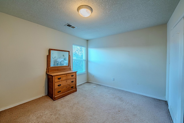 bedroom with light carpet and a textured ceiling