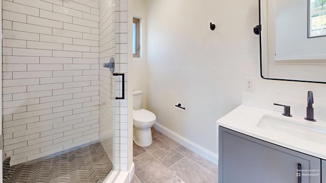 bathroom featuring vanity, toilet, and tiled shower