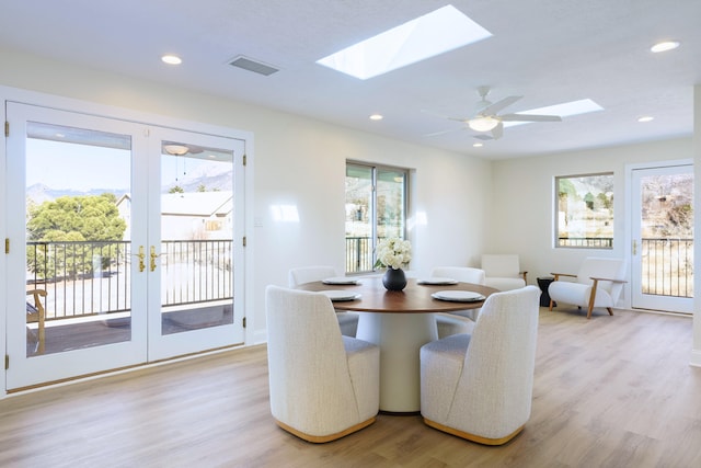 dining room featuring a skylight, light hardwood / wood-style flooring, and french doors