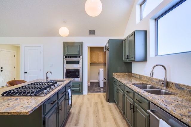 kitchen featuring stainless steel appliances, light stone countertops, sink, and light wood-type flooring