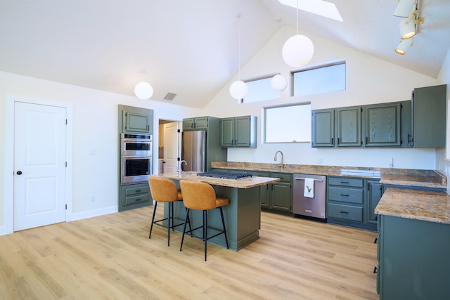 kitchen featuring sink, a breakfast bar area, decorative light fixtures, appliances with stainless steel finishes, and a kitchen island