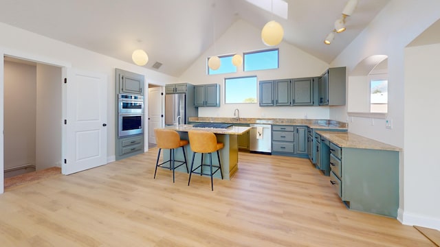 kitchen with decorative light fixtures, a kitchen bar, a center island, light stone counters, and stainless steel appliances