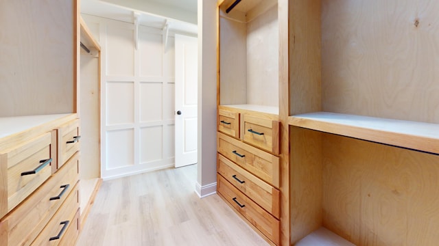 walk in closet with light hardwood / wood-style floors