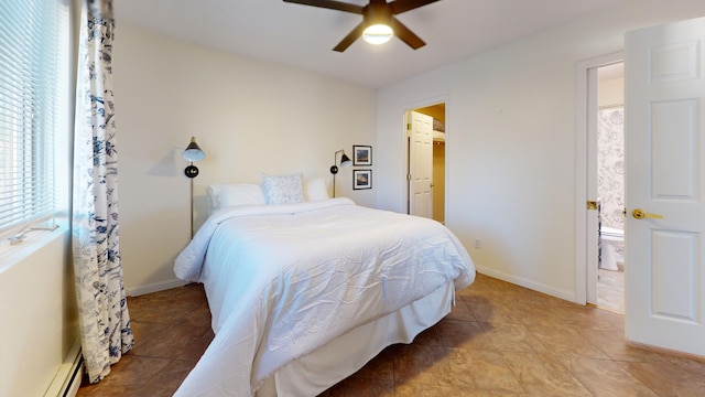 bedroom featuring a baseboard heating unit, ensuite bath, a walk in closet, and ceiling fan