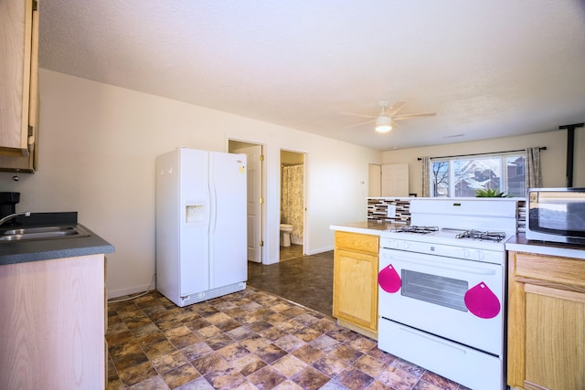 kitchen with ceiling fan, white appliances, light brown cabinetry, and sink