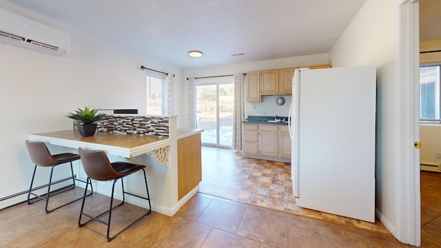 kitchen featuring sink, a breakfast bar, a wall mounted AC, light brown cabinetry, and white fridge