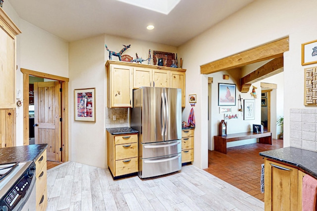 kitchen with tasteful backsplash, stove, light brown cabinetry, and stainless steel refrigerator