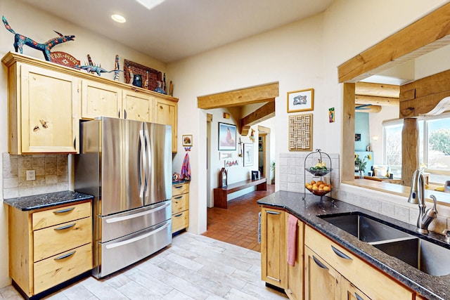 kitchen with sink, decorative backsplash, stainless steel fridge, and light brown cabinets