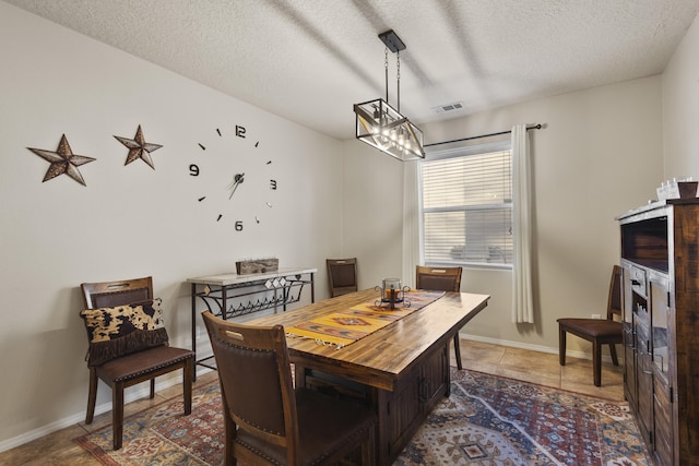 dining space with tile patterned flooring, a notable chandelier, and a textured ceiling