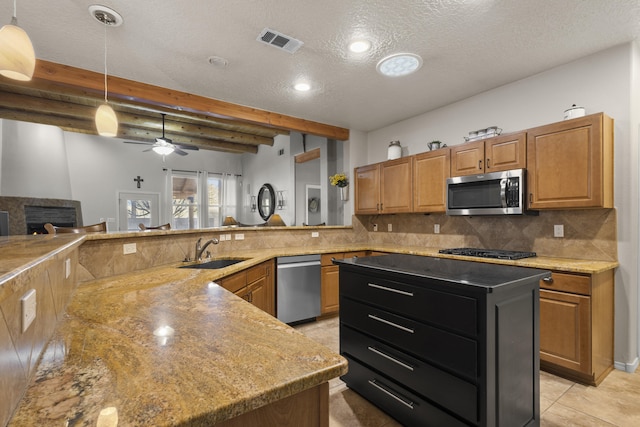 kitchen with sink, tasteful backsplash, light stone counters, hanging light fixtures, and stainless steel appliances