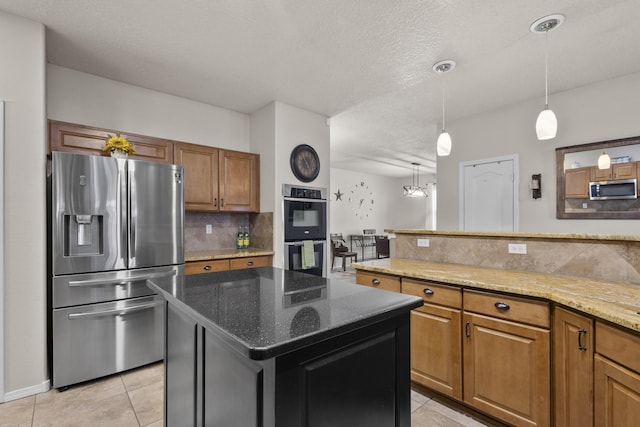 kitchen featuring appliances with stainless steel finishes, tasteful backsplash, a center island, light tile patterned floors, and light stone counters