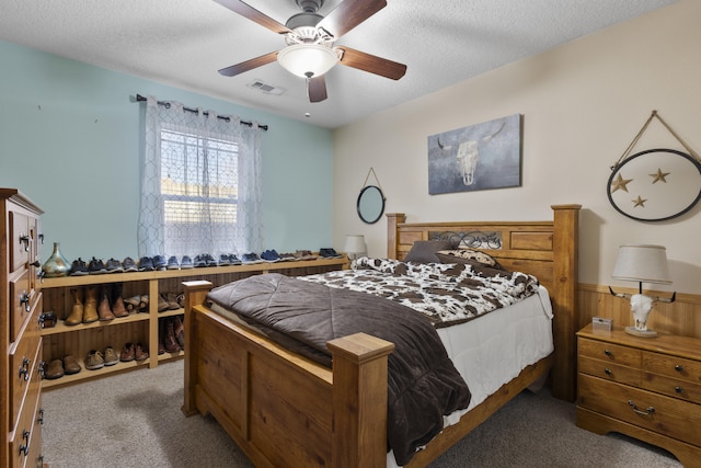 carpeted bedroom with ceiling fan and a textured ceiling