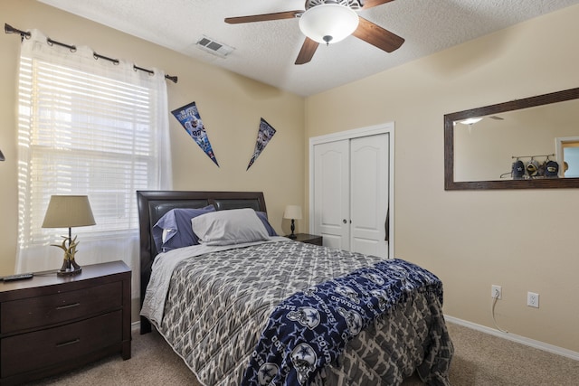 bedroom featuring ceiling fan, light colored carpet, a closet, and a textured ceiling