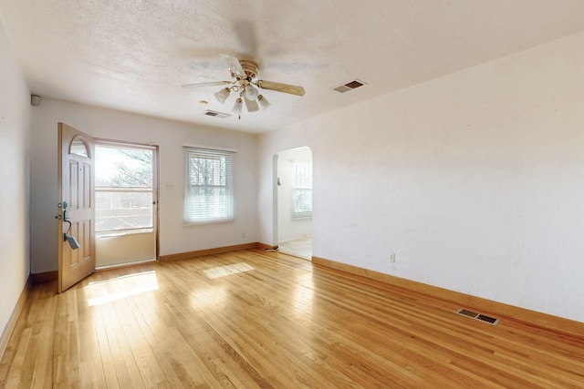 empty room featuring ceiling fan, a textured ceiling, and light wood-type flooring