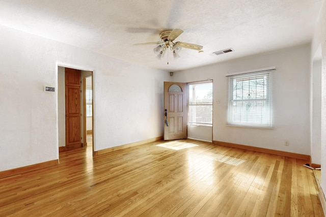 empty room with a textured ceiling, ceiling fan, and light hardwood / wood-style flooring