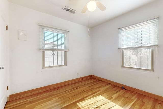 spare room featuring ceiling fan, a wealth of natural light, and light hardwood / wood-style floors