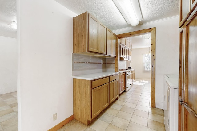 kitchen featuring stainless steel range, light tile patterned floors, decorative backsplash, and a textured ceiling