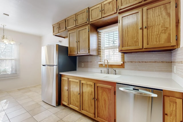 kitchen featuring sink, decorative light fixtures, light tile patterned floors, appliances with stainless steel finishes, and backsplash