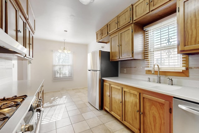 kitchen with light tile patterned floors, sink, appliances with stainless steel finishes, hanging light fixtures, and a notable chandelier