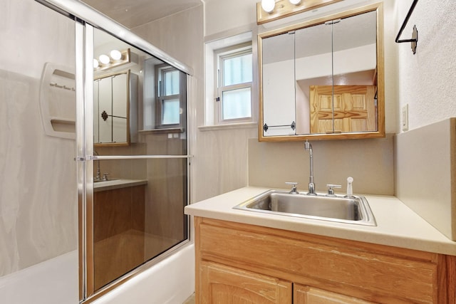 bathroom featuring bath / shower combo with glass door and sink