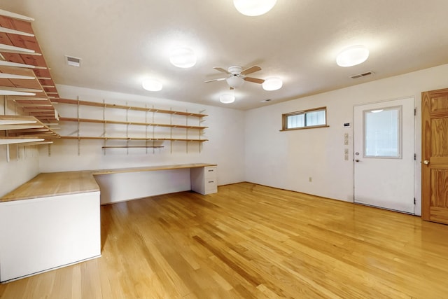 interior space featuring ceiling fan, built in desk, and light wood-type flooring