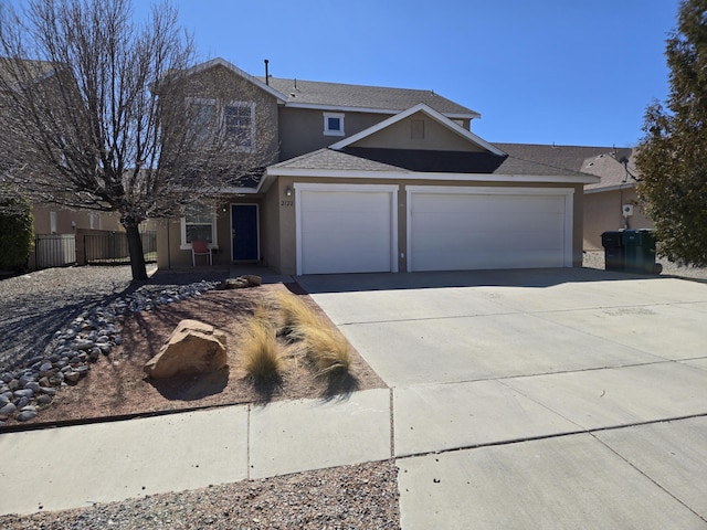 traditional-style house featuring a garage, driveway, fence, and stucco siding