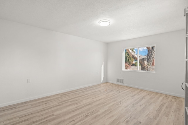 spare room featuring a textured ceiling and light hardwood / wood-style flooring