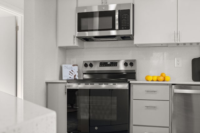 kitchen with appliances with stainless steel finishes, white cabinets, and backsplash