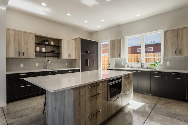 kitchen with wall oven, a center island, backsplash, sink, and a kitchen bar