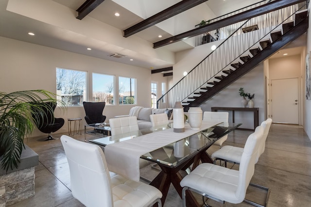 dining space featuring beamed ceiling and concrete flooring