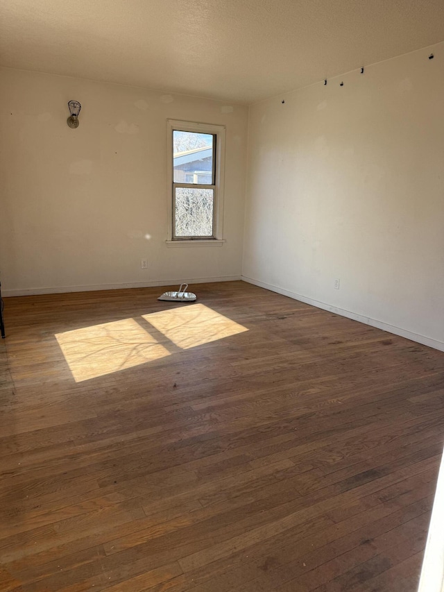 empty room with baseboards and dark wood-type flooring