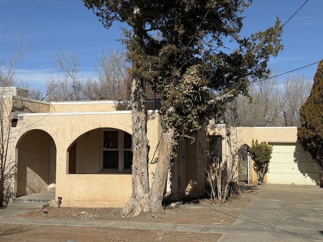 view of front of property with a garage, concrete driveway, and stucco siding