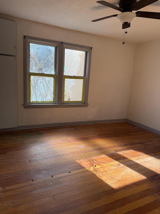spare room featuring ceiling fan, hardwood / wood-style floors, and baseboards