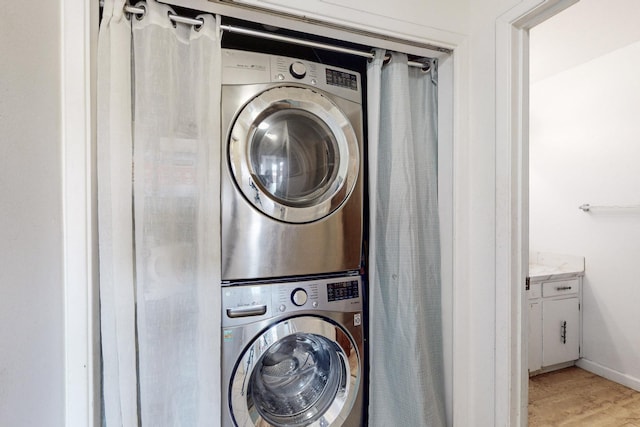 clothes washing area with stacked washer and clothes dryer and light hardwood / wood-style floors