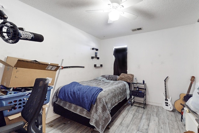 bedroom with ceiling fan, wood-type flooring, and a textured ceiling