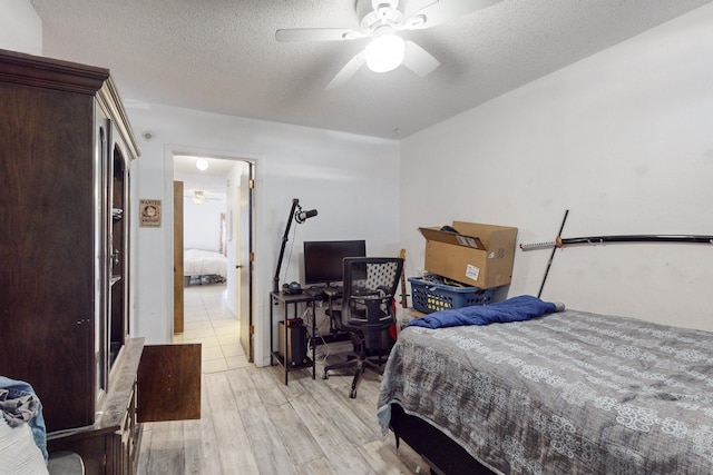 bedroom with ceiling fan, light hardwood / wood-style flooring, and a textured ceiling