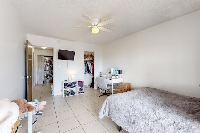 tiled bedroom with stacked washer / dryer, a spacious closet, a textured ceiling, and a closet