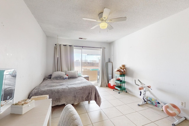 bedroom with ceiling fan, light tile patterned floors, a textured ceiling, and access to outside