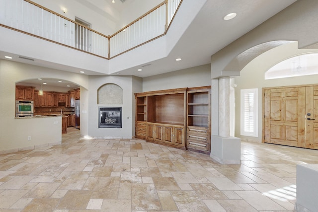 unfurnished living room featuring a towering ceiling