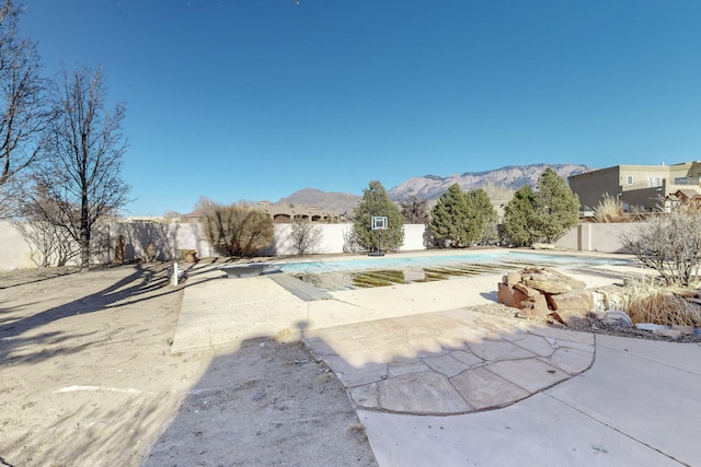 exterior space with a mountain view, a patio area, and a covered pool