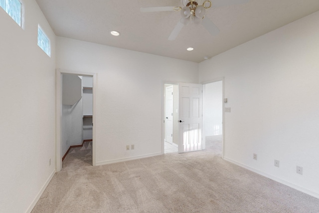 unfurnished bedroom with ceiling fan, light colored carpet, and a walk in closet