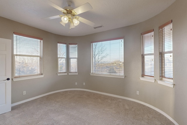 spare room with carpet flooring, a wealth of natural light, and ceiling fan