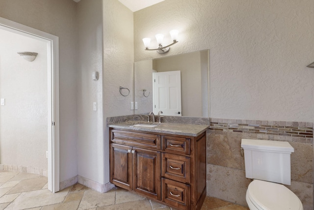 bathroom with vanity, tile walls, and toilet