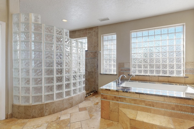 bathroom with a tile shower and a textured ceiling