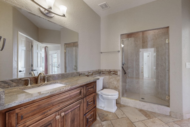 bathroom featuring vanity, a shower with door, toilet, and tile walls