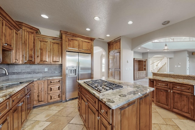 kitchen featuring stainless steel appliances, tasteful backsplash, a center island, and light stone counters