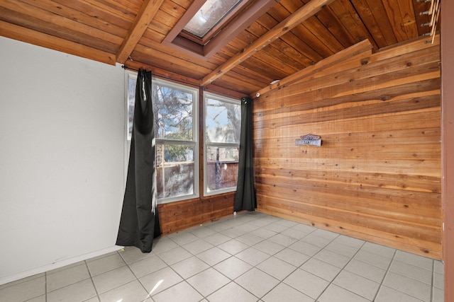 spare room with wood walls, vaulted ceiling with skylight, light tile patterned floors, and wooden ceiling