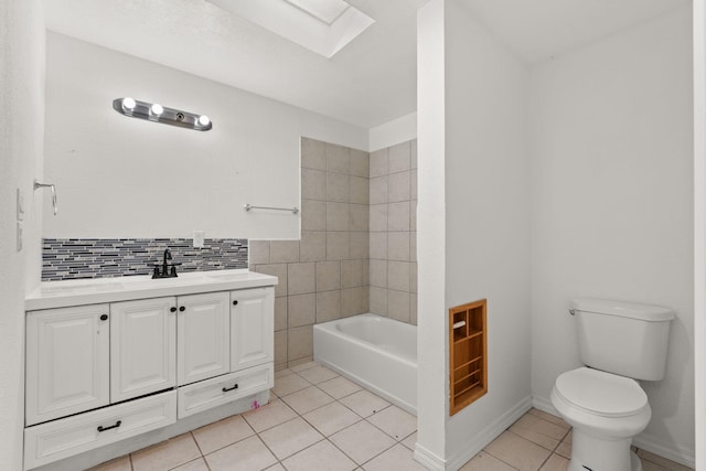 bathroom with a skylight, a tub to relax in, vanity, toilet, and tile patterned floors