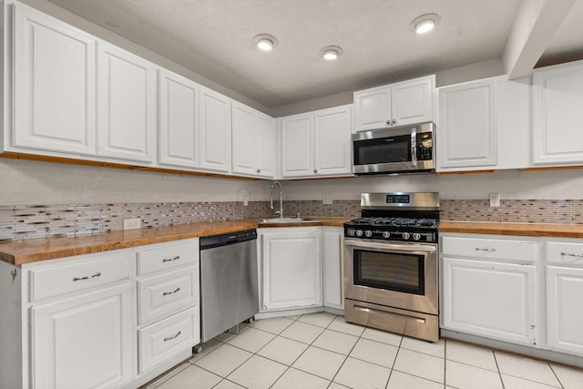 kitchen with white cabinetry, appliances with stainless steel finishes, sink, and butcher block countertops