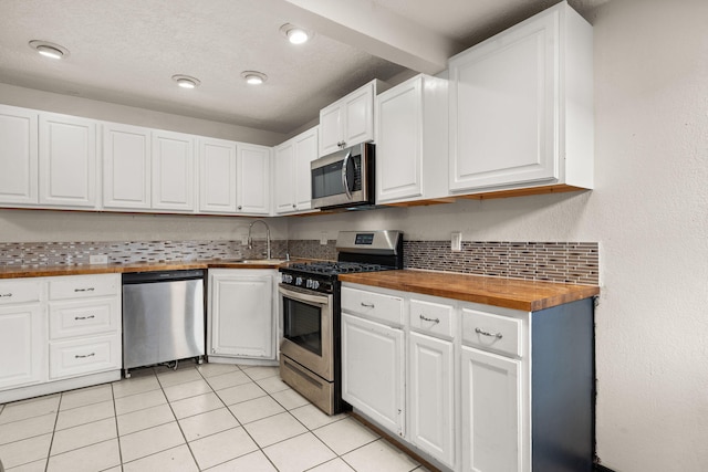 kitchen with butcher block counters, sink, white cabinetry, and stainless steel appliances